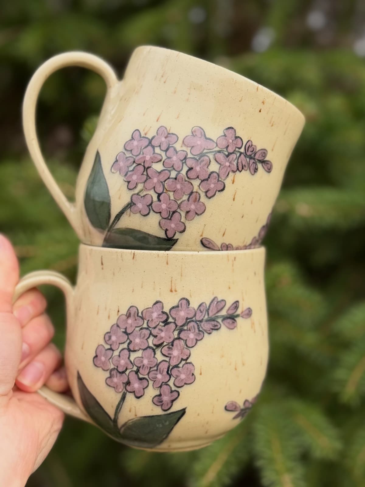 Two hand-painted lilac ceramic mugs stacked together
